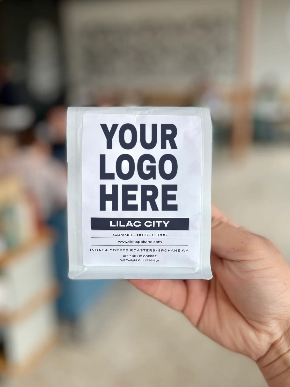 Hand holding an 8oz custom coffee gift bag with a Your Logo Here label