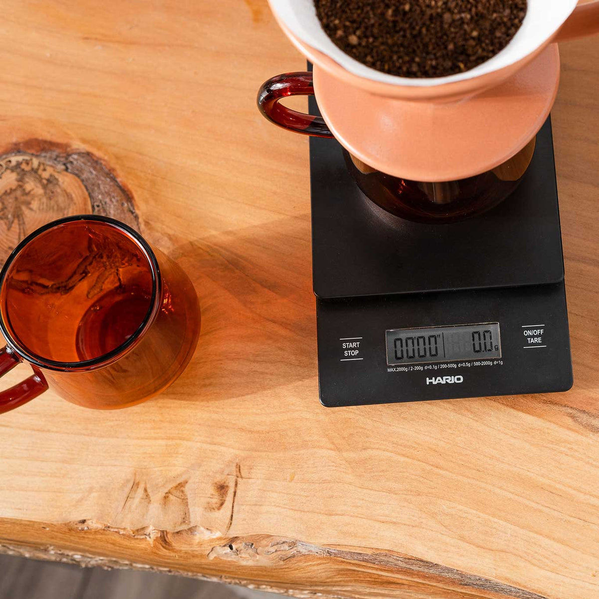 Black Hario drip scale under a pour-over dripper on a wooden board
